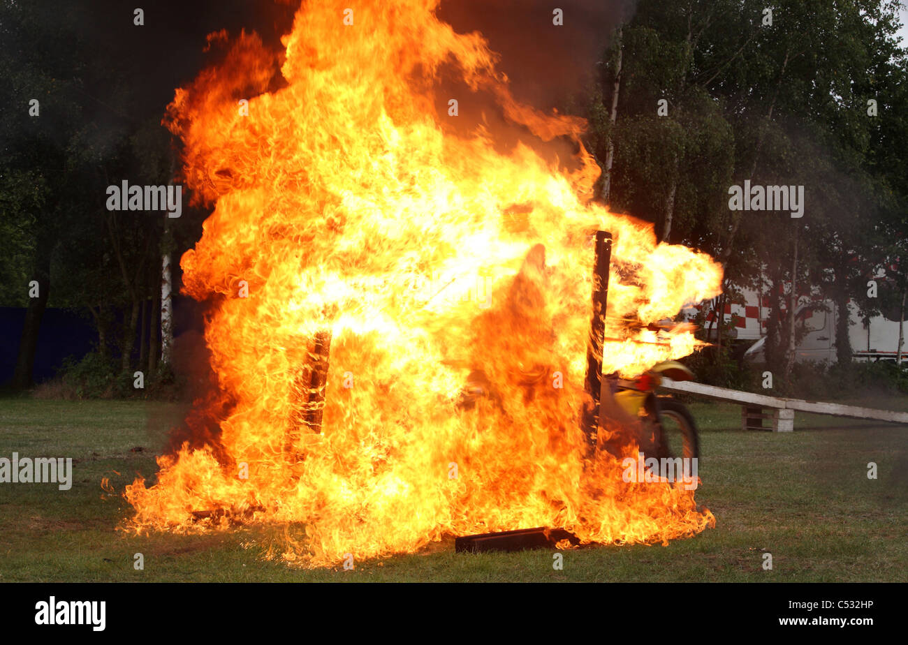 Stunt rider passando attraverso la parete di fiamme Foto Stock