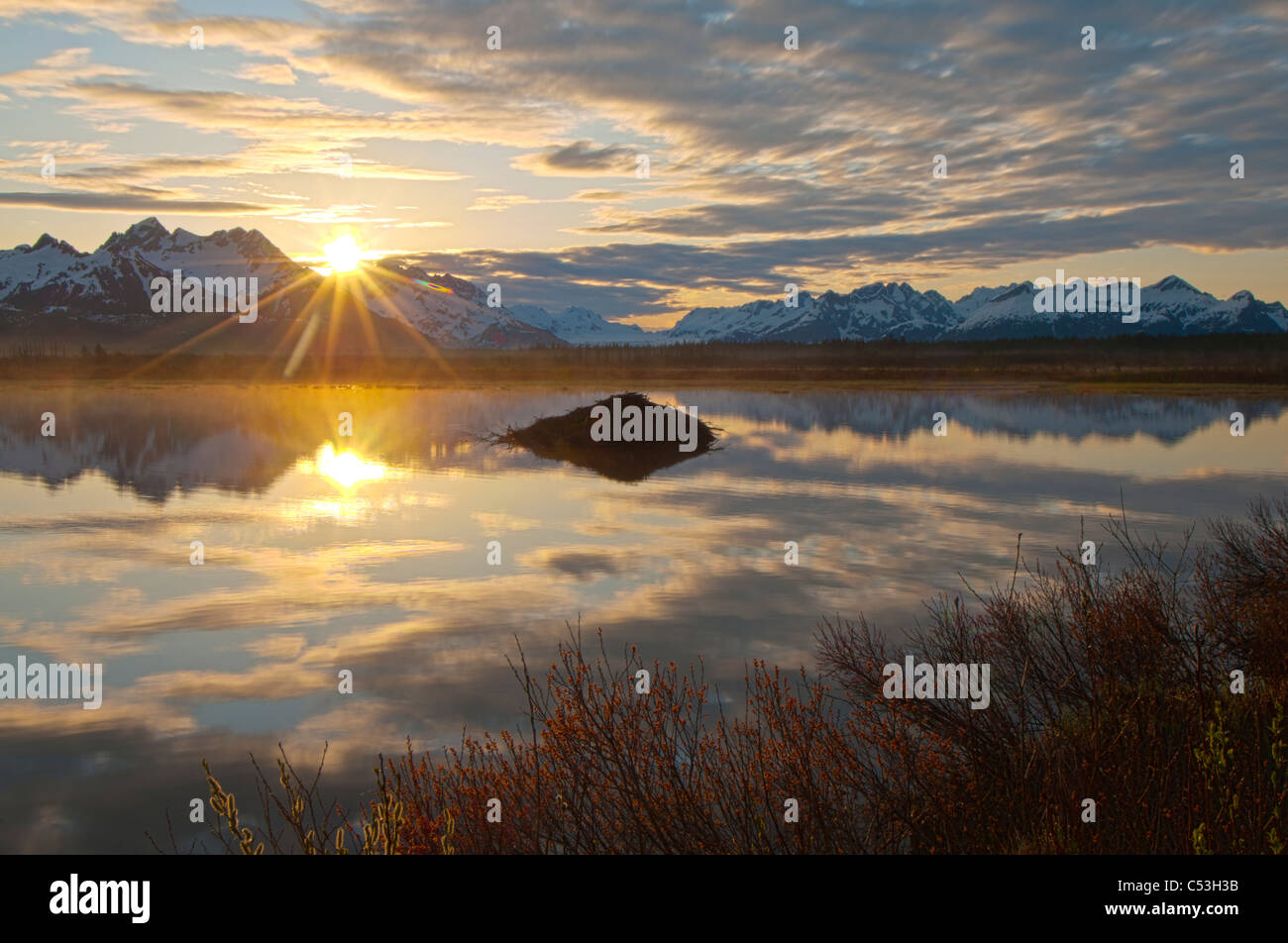 Sole sorge su Chugach Mountains con laghetto e beaver lodge in primo piano, Chugach National Forest, Alaska Foto Stock