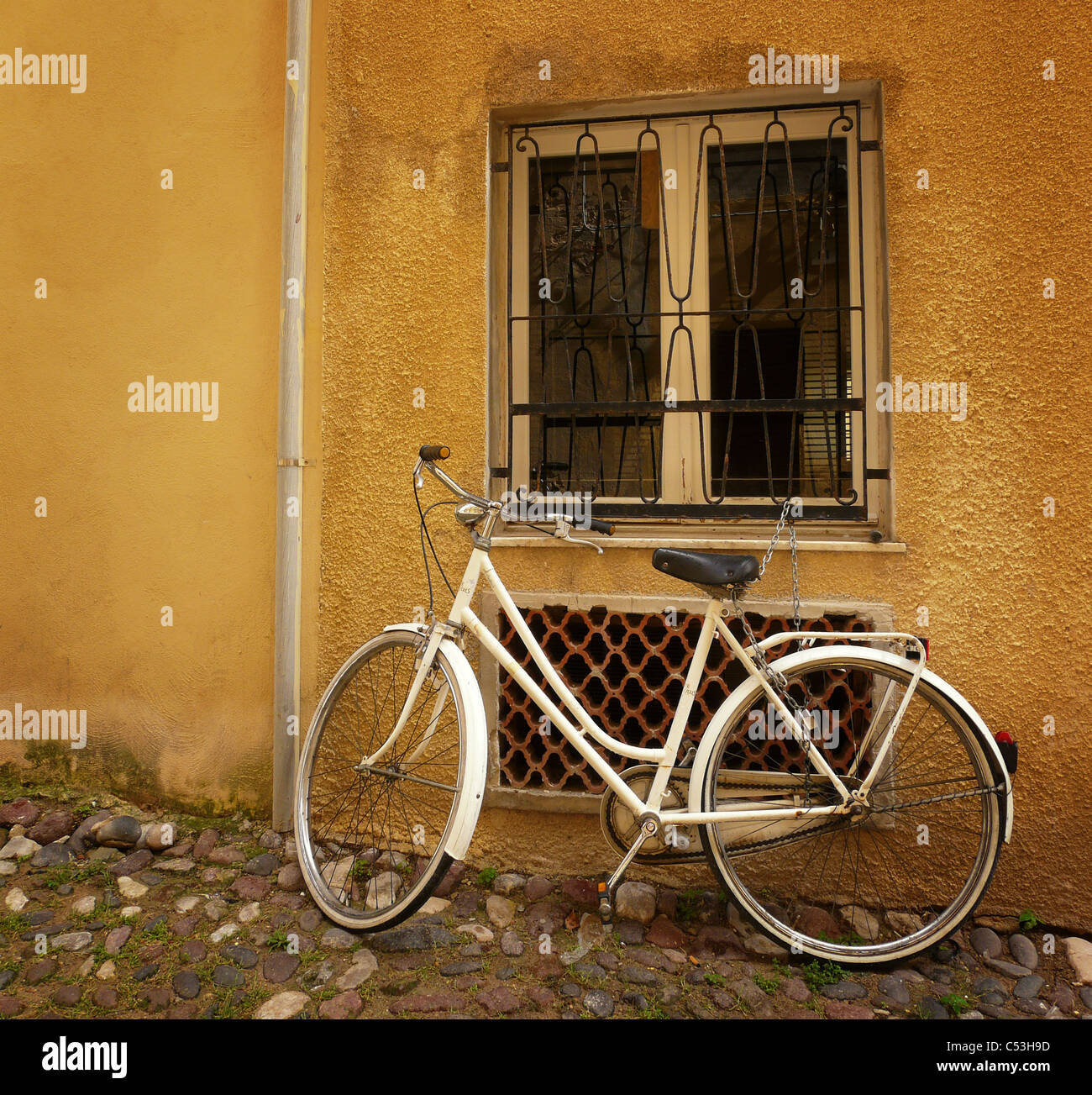Vecchia bicicletta in piedi contro un muro al di sotto di una finestra. Foto Stock