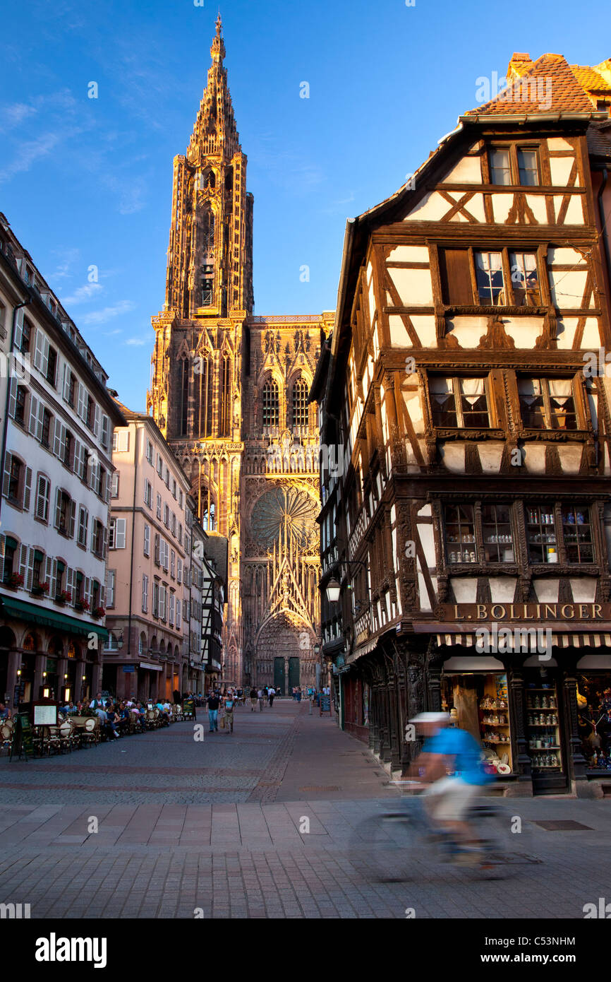 Bicycler passa accanto alla massiccia Cattedrale di Notre Dame a Strasburgo, Bas Rhin, Alsazia, Francia Foto Stock