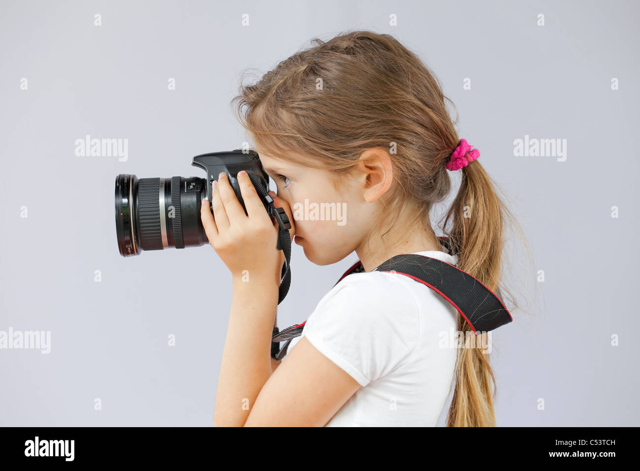 Sette anni di ragazza che utilizza una fotocamera digitale SLR Foto Stock