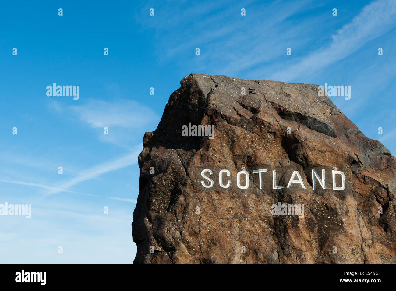 Scozia pietra di confine al confine di Northumberland davanti a una croce bianca piano trail nel cielo blu Foto Stock