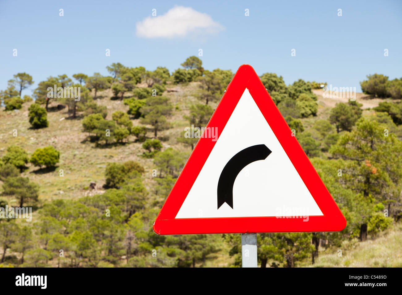 Un segno di piegatura su una stretta strada di montagna nelle montagne della Sierra Nevada della Spagna meridionale. Foto Stock