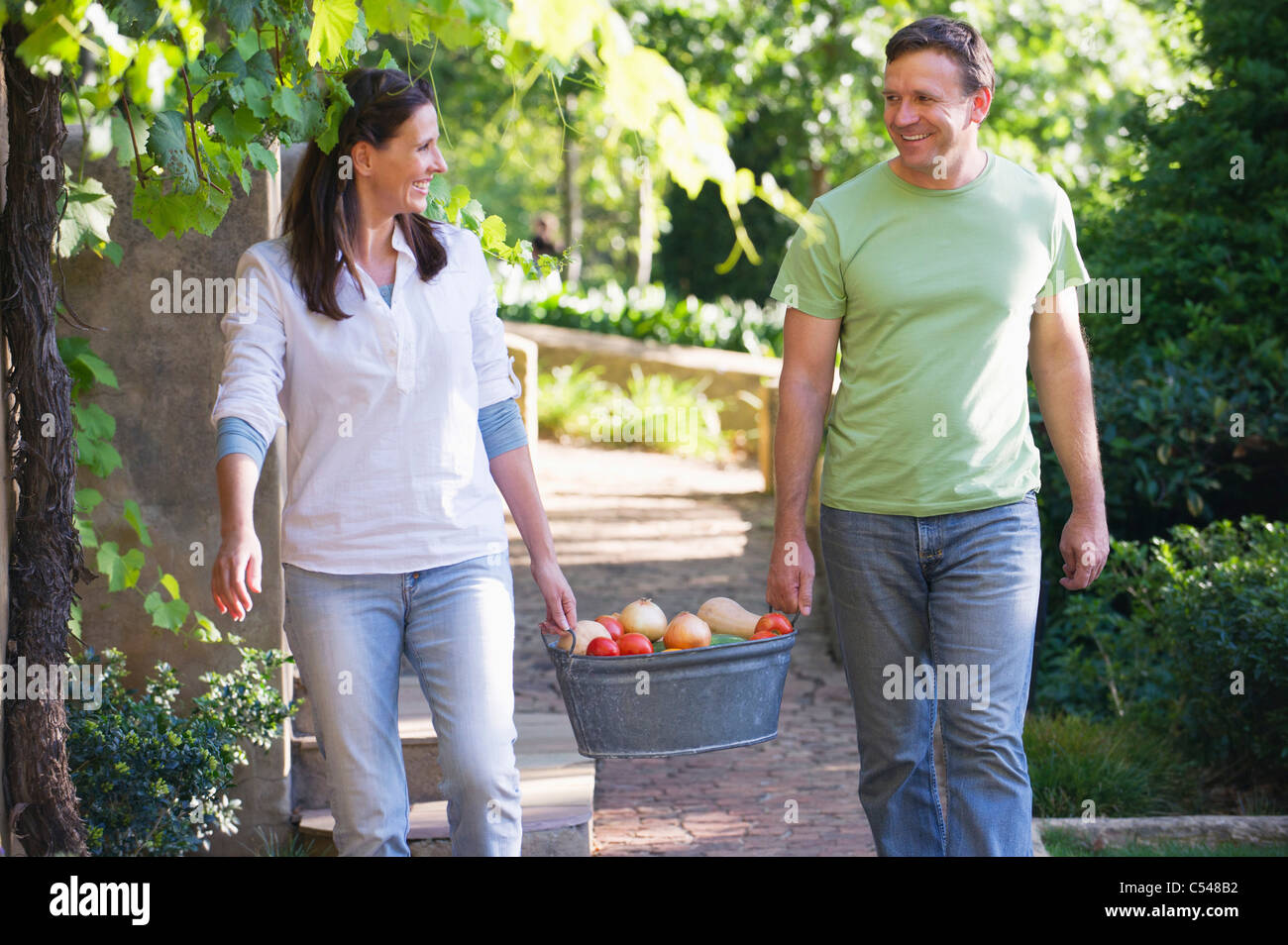 Coppia matura portante cesta di frutta in un giardino Foto Stock
