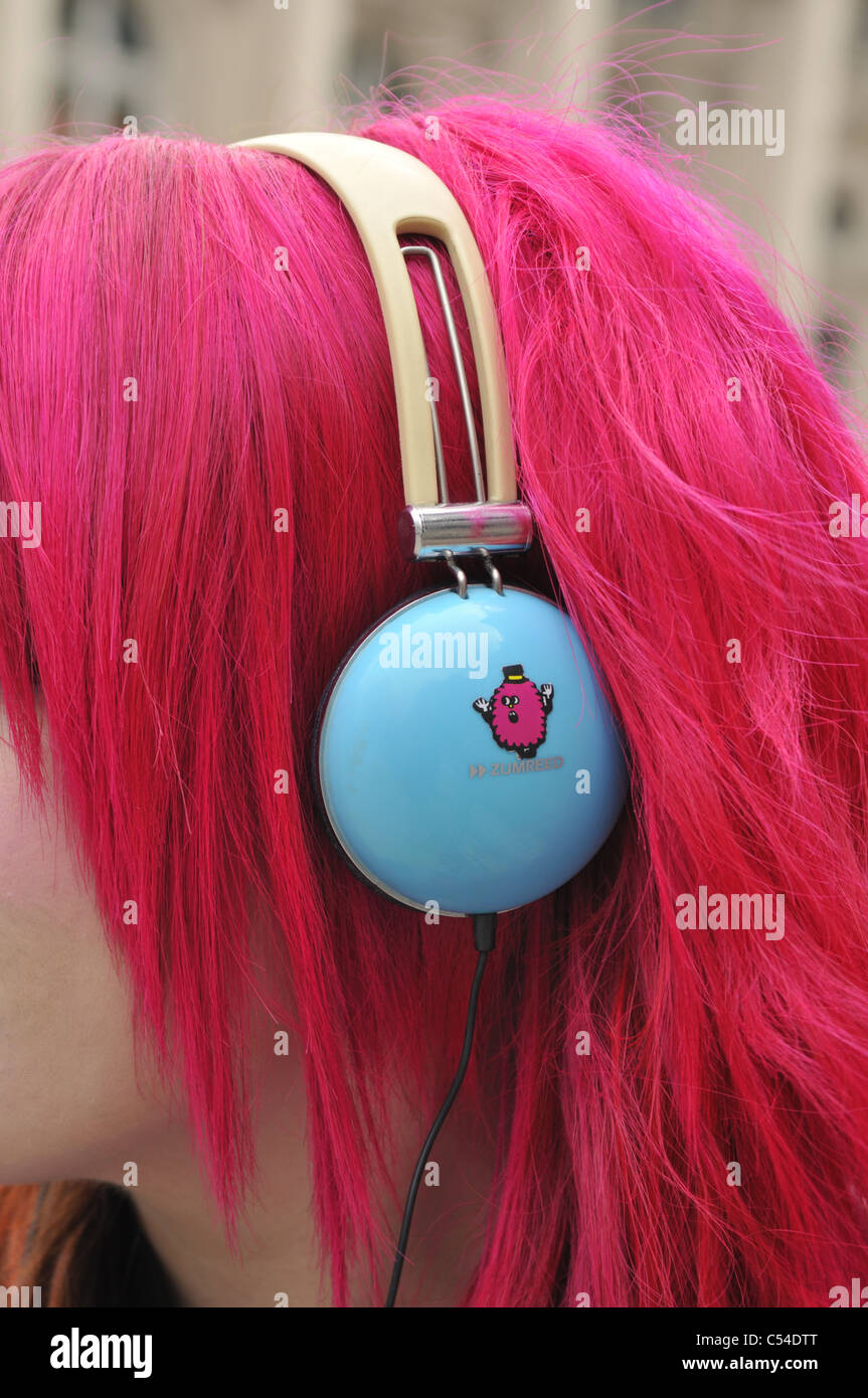 Ragazza con rosa capelli tinti e cuffie blu a Piccadilly, Londra, Regno Unito. Foto Stock