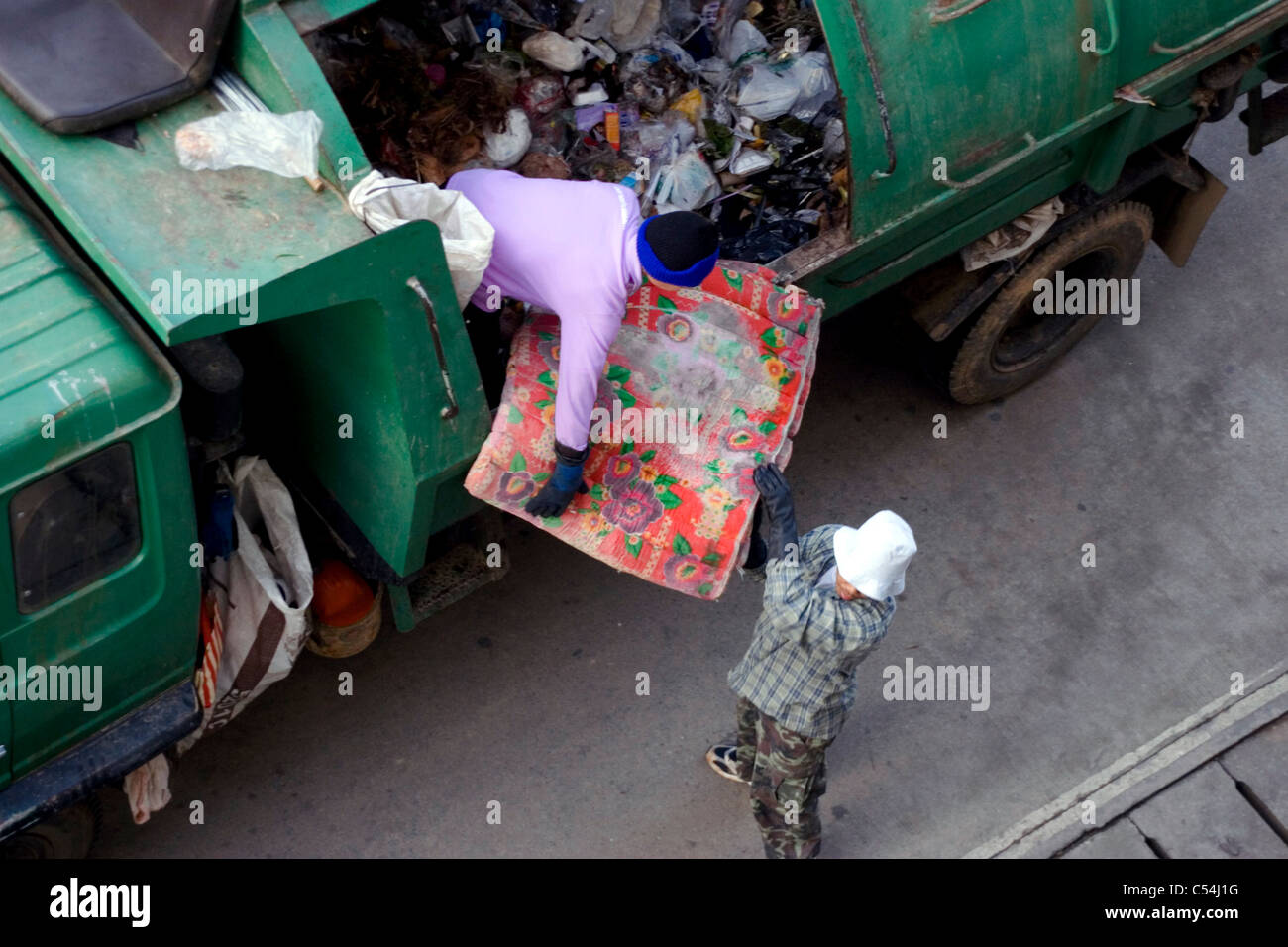 Due uomini sono in fase di carico di un camion della spazzatura con cestino su una strada di città in Mae Sai, (SAE) Thailandia. Foto Stock