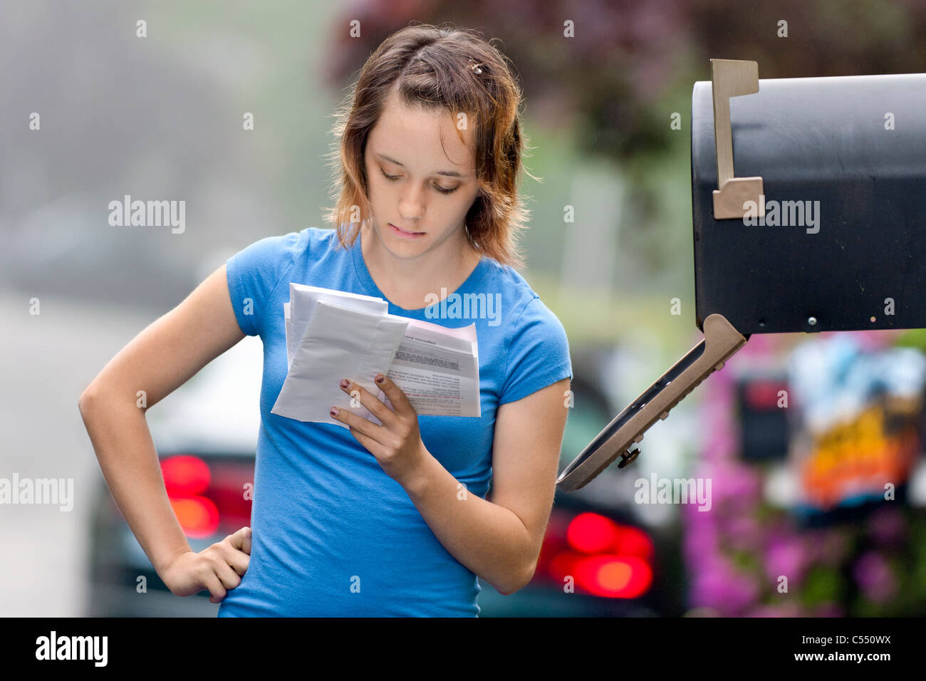 Ragazza adolescente leggere la posta dalla cassetta postale. Foto Stock