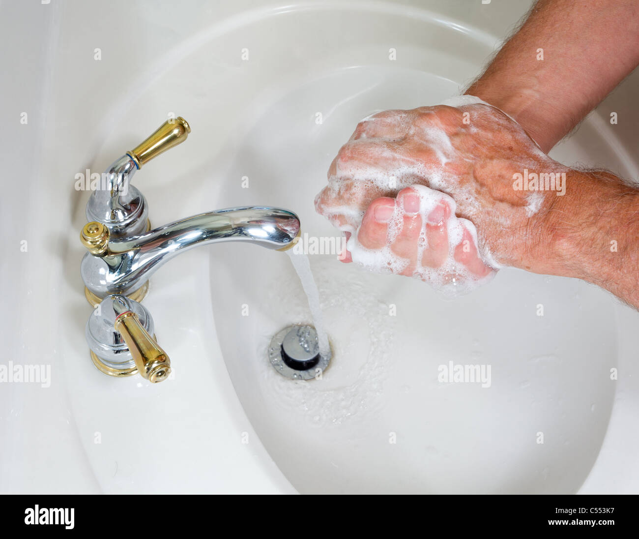 Uomo senior di lavarsi le mani nel lavabo moderno con sapone e di formazione di schiuma saponata Foto Stock
