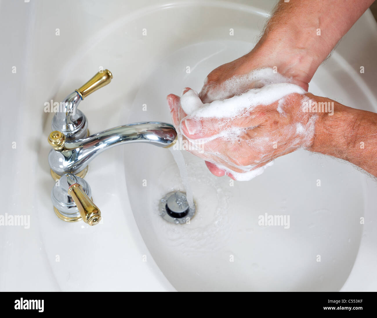 Lavare le mani in un lavandino del bagno Foto Stock