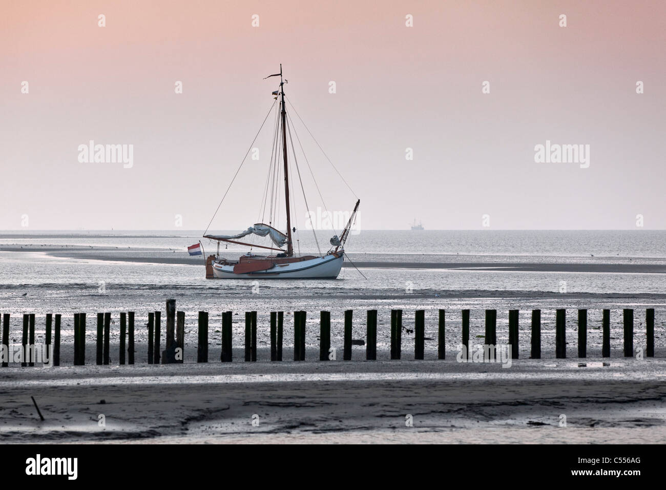 I Paesi Bassi, il Nes Ameland, Isola, appartenente al mare di Wadden Islands. Imbarcazione a vela sulla piana di fango nel porto. Foto Stock