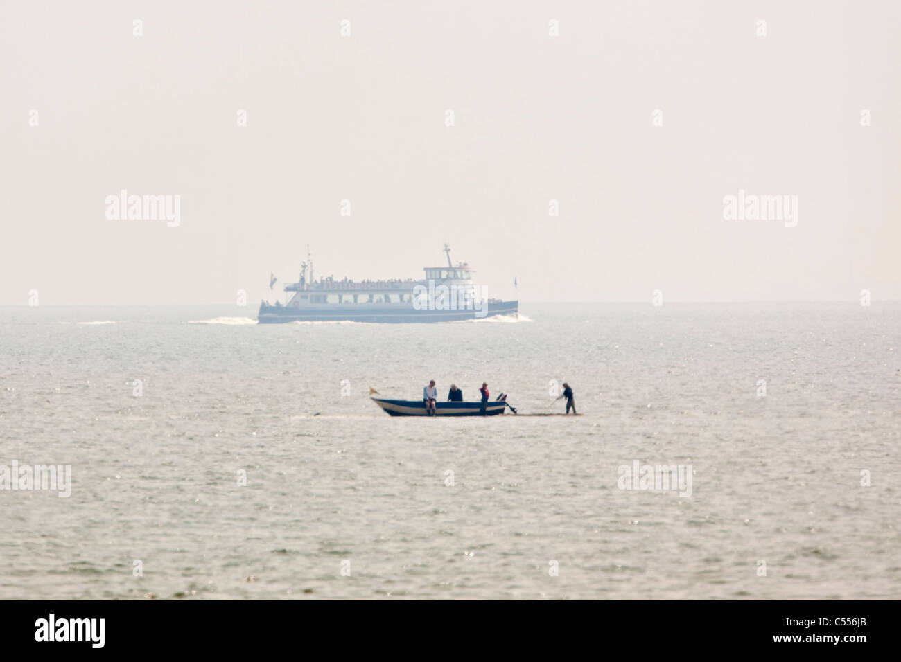 I Paesi Bassi, Hollum, Ameland isola, il Wadden Sea Isole. Piccola barca sulla piana di fango e tour in barca in background. Foto Stock