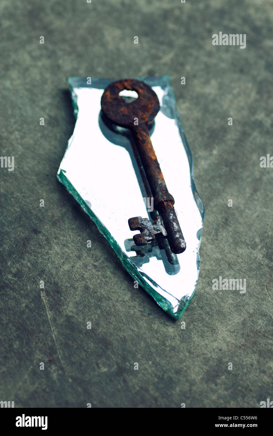 Vecchia chiave arrugginita su un pezzo di specchio rotto Foto Stock