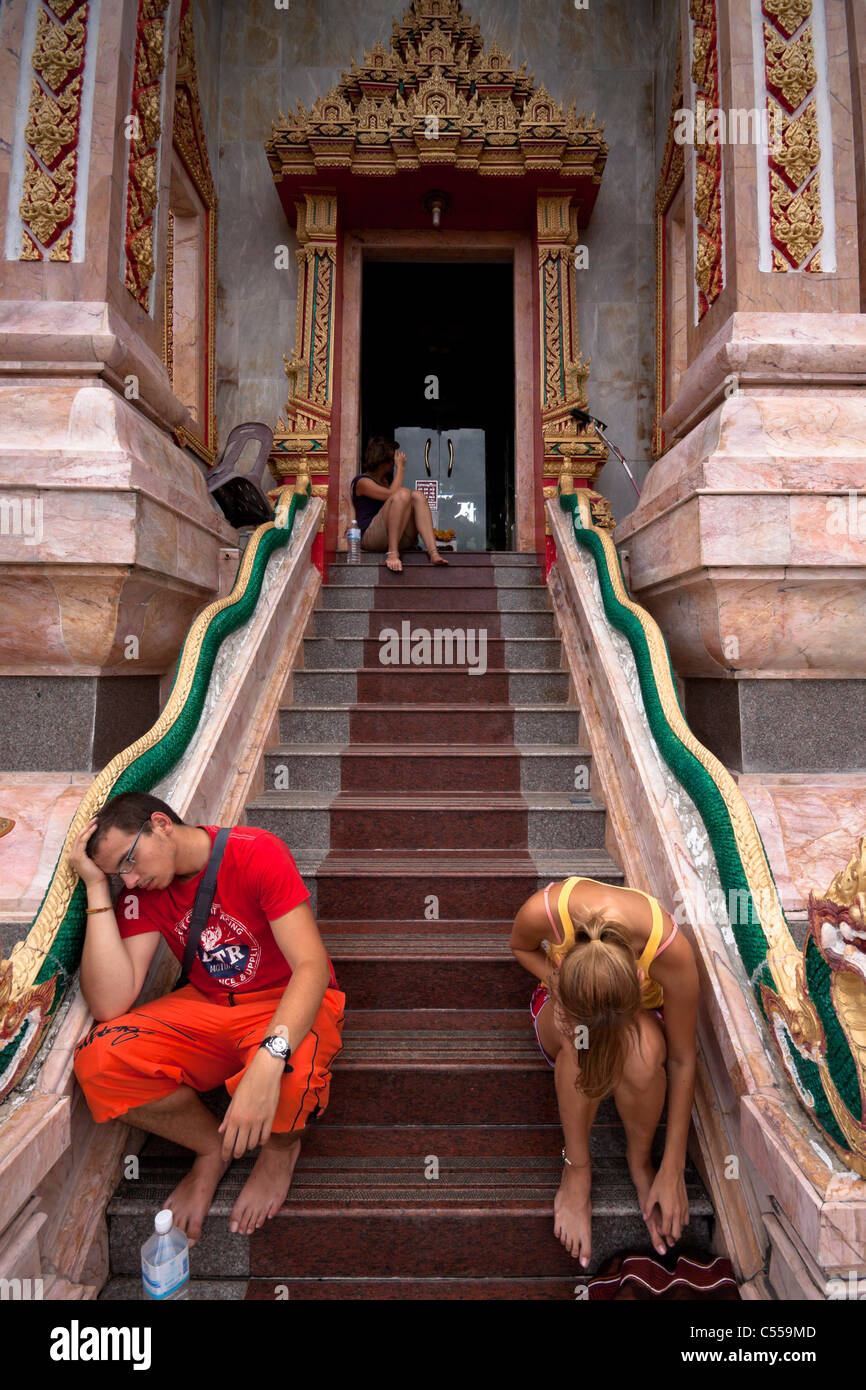 Stanco di turisti europei appoggiata all'ingresso al Wat Chalong - tempio buddista a Phuket, Tailandia. Foto Stock