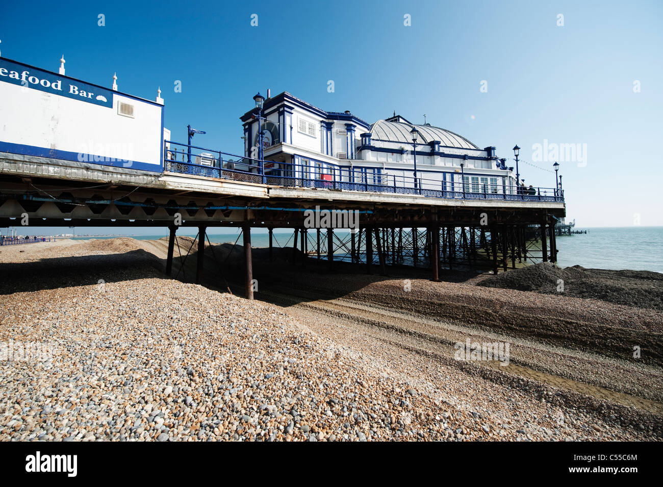 Sostituzione di scandole per fermare l'erosione costiera sulla spiaggia a Eastbourne con edifici sul molo vittoriano al di sopra Foto Stock