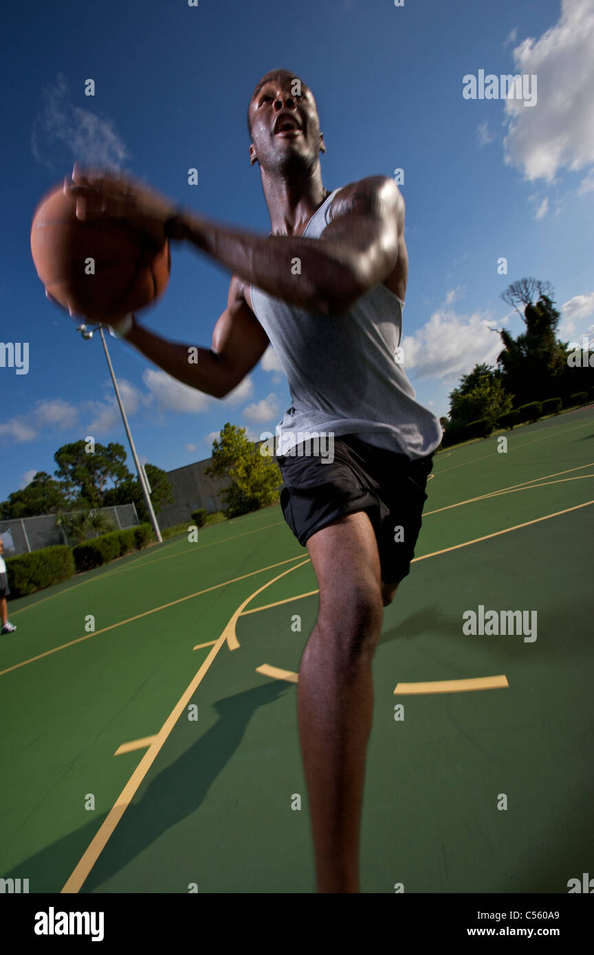 Guida maschio all'aperto durante il gioco del basket Foto Stock