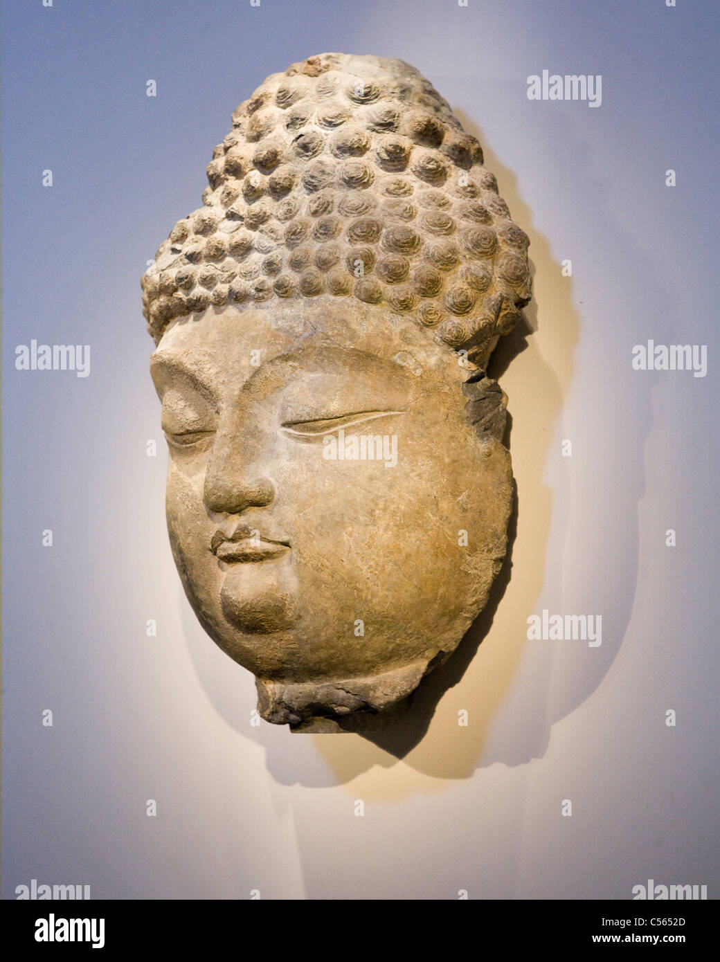 La scultura in pietra di Buddha appeso alla parete Foto Stock
