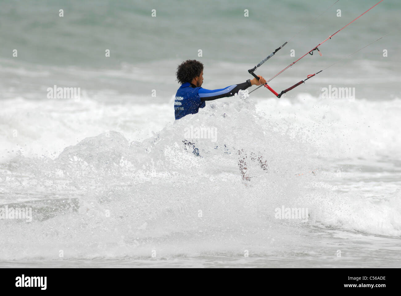 Surfista kite surfing attraverso break in spiaggia Foto Stock