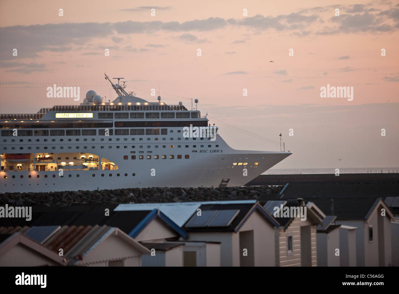 I Paesi Bassi, IJmuiden, nave da crociera che arrivano al mare del Nord Canal. Sunrise. Cabine da spiaggia. Foto Stock
