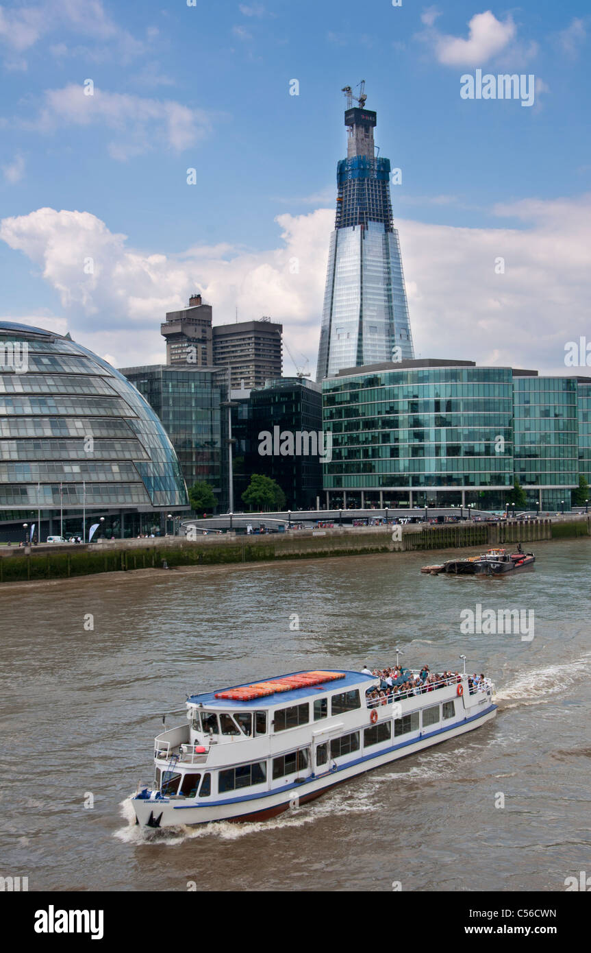 La barca turistica sul fiume Tamigi con il Coccio edificio in background. Londra. Regno Unito. Foto Stock