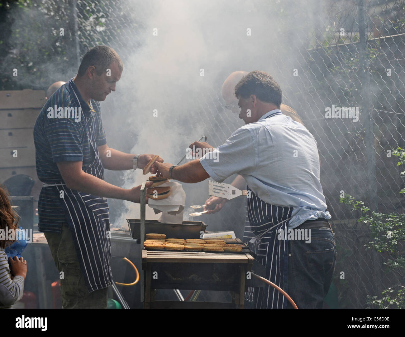 Un sacco di fumo come uomini cucinare al barbecue presso la Comunità Patchfest evento festival a Brighton Regno Unito Foto Stock