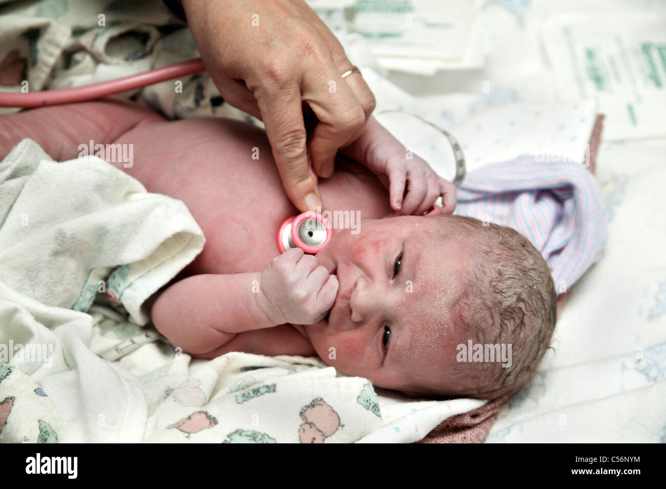 Neonato, ostetrica utilizzando uno stetoscopio Foto Stock