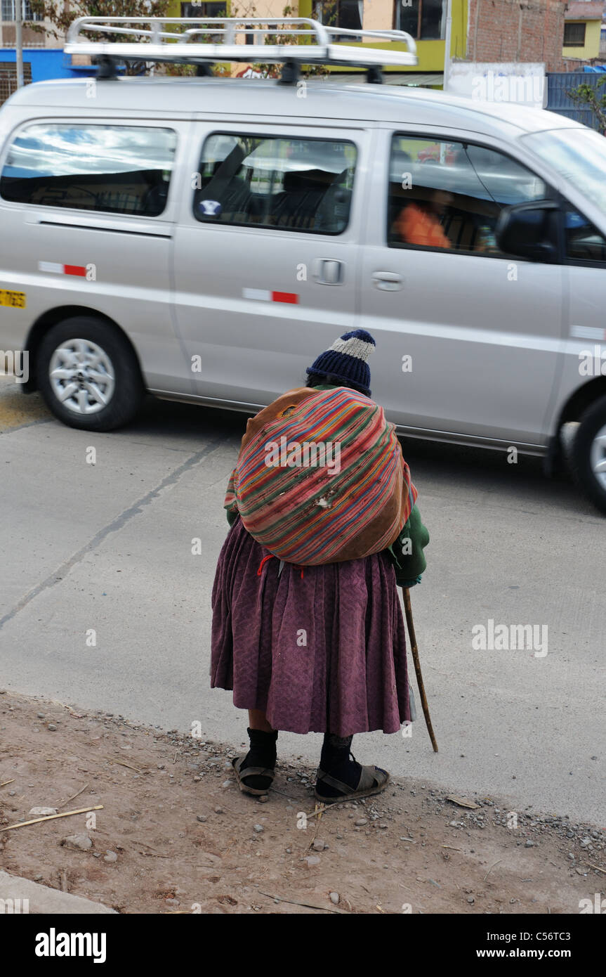 Un molto vecchio e piegate la donna sta tentando di attraversare una strada trafficata in Cusco, Perù Foto Stock