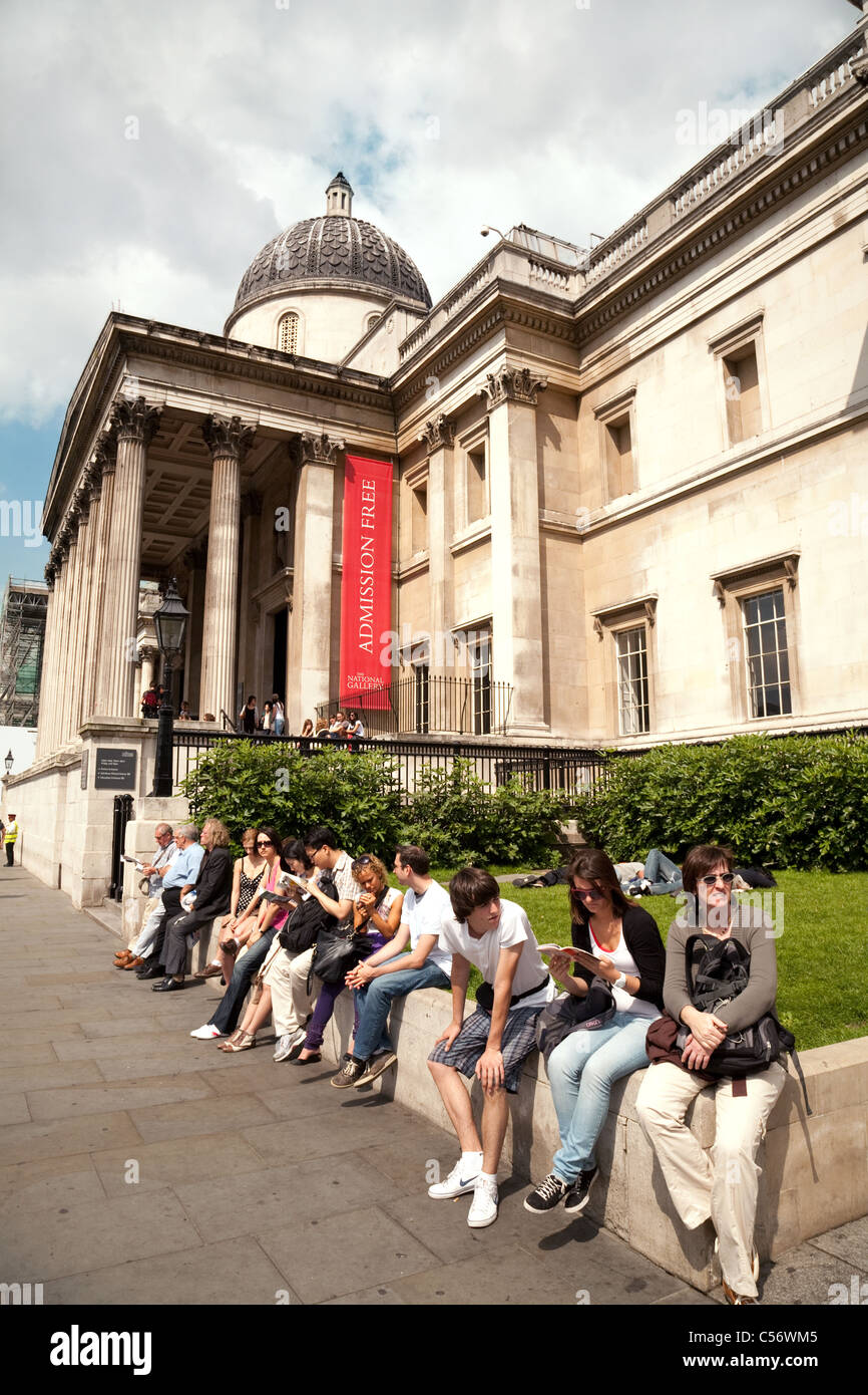 Gli adolescenti al di fuori seduta alla National Gallery, Trafalgar Square, London REGNO UNITO Foto Stock