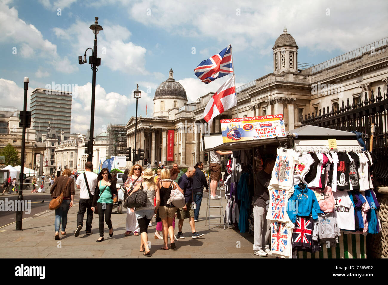 La gente camminare passato souvenir turistici di bancarelle, Trafalgar Square, London REGNO UNITO Foto Stock