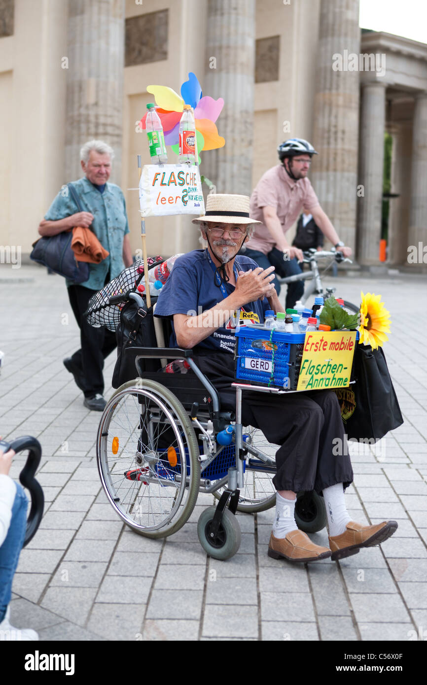 Uomo in sedia a rotelle il prelievo di deposito di bottiglie per qualche cambiamento a Berlino presso la Porta di Brandeburgo, Germania Foto Stock