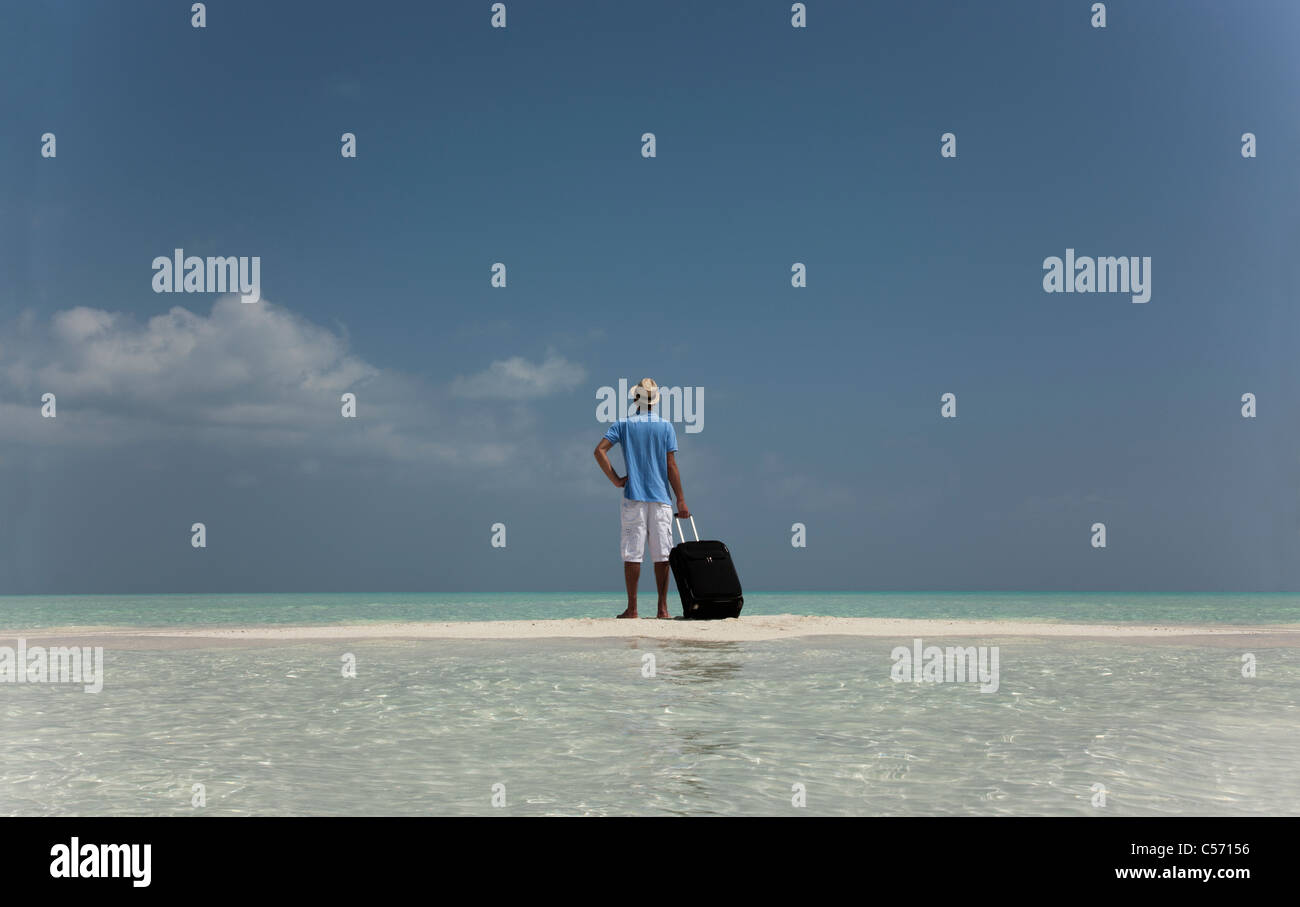 Uomo perduto con i bagagli sulla spiaggia Foto Stock