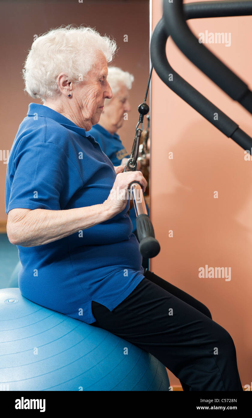 Donna anziana utilizzando macchina ginnica Foto Stock