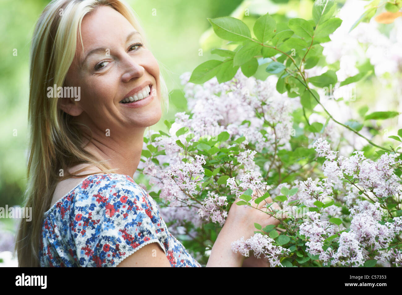 Donna sorridente a caccia di fiori Foto Stock