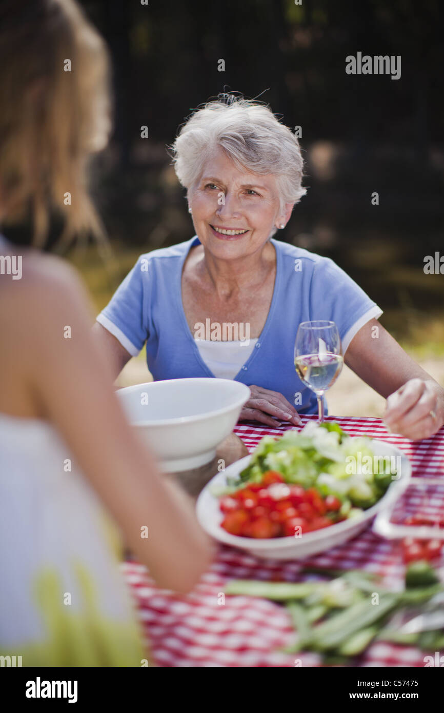 I vecchi donna seduta al tavolo da picnic Foto Stock