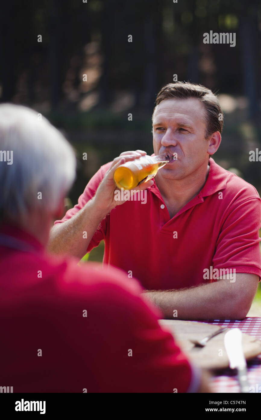 Uomo di bere birra al tavolo da picnic Foto Stock