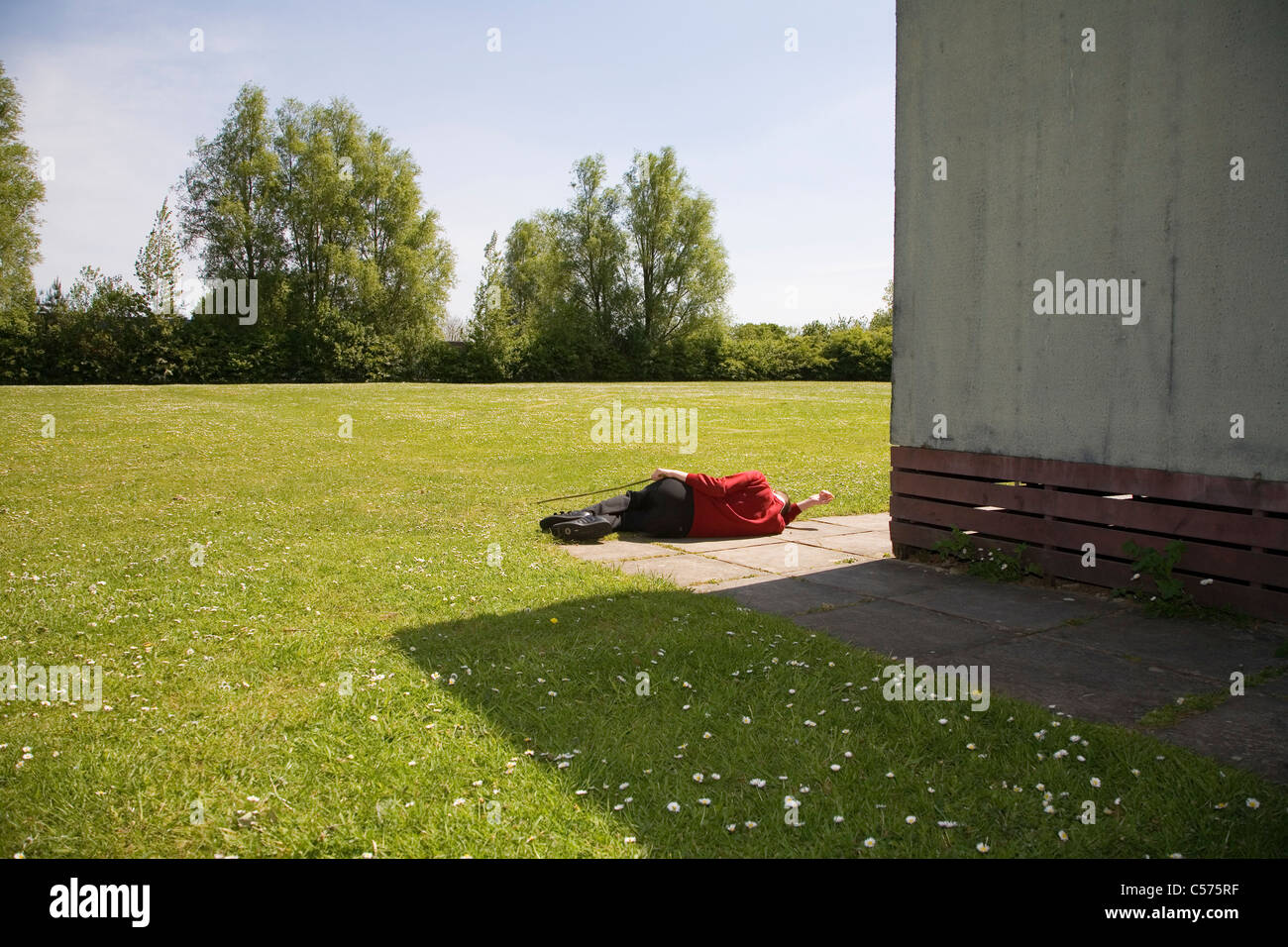 Ragazzo con bisogni speciali sdraiato in campo scolastico Foto Stock