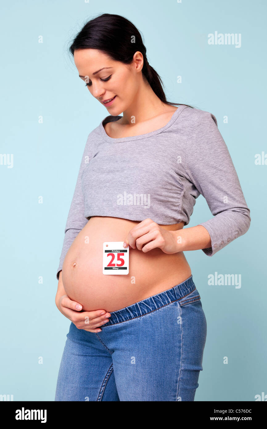 Foto di una settimana 32 donna incinta tenendo la data del suo bambino è dovuto contro il suo ventre, aggiungere la vostra data se necessario. Foto Stock