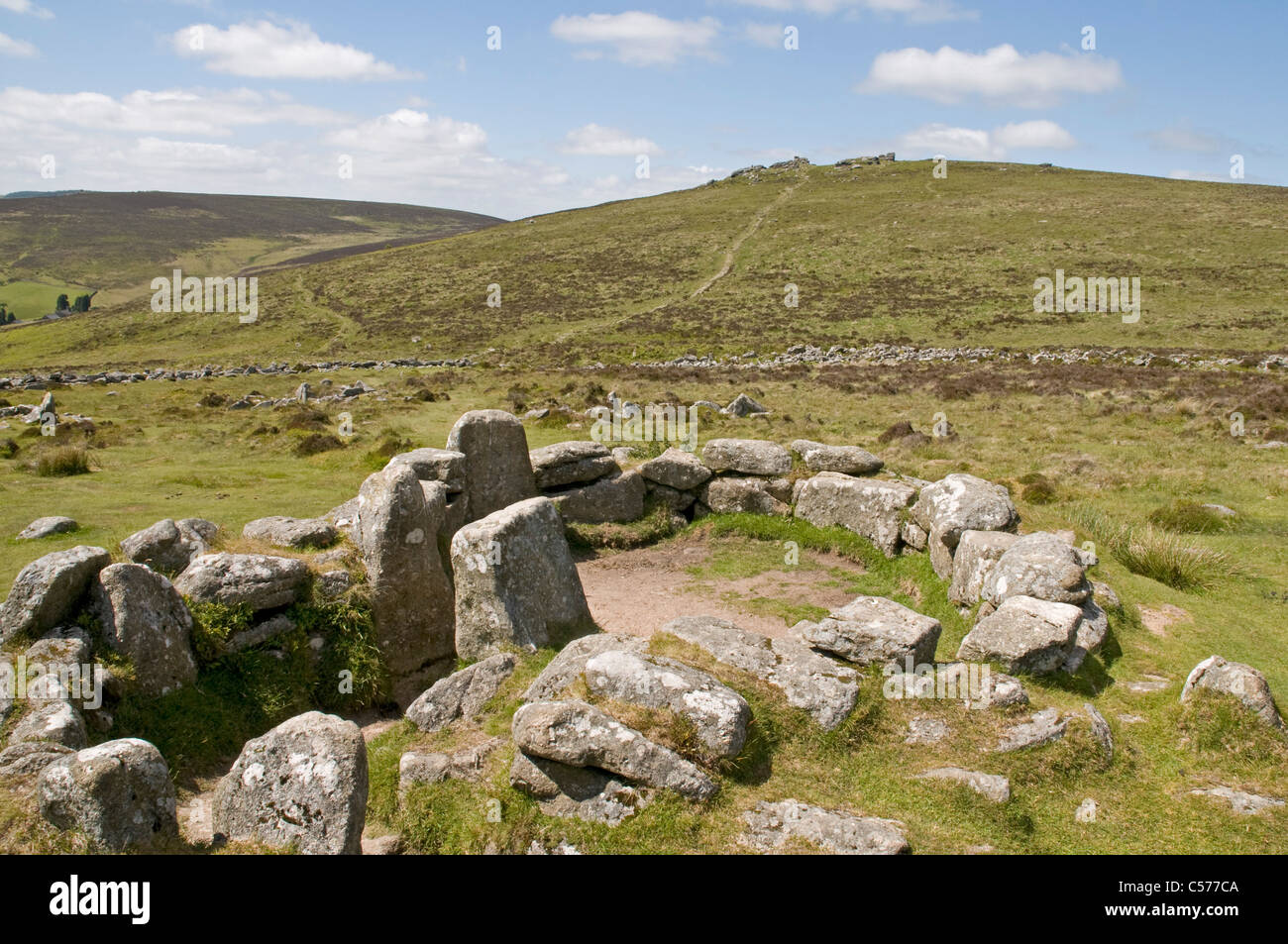 Resti della tarda età del bronzo insediamento di Grimspound su Dartmoor con Hookney Tor oltre Foto Stock