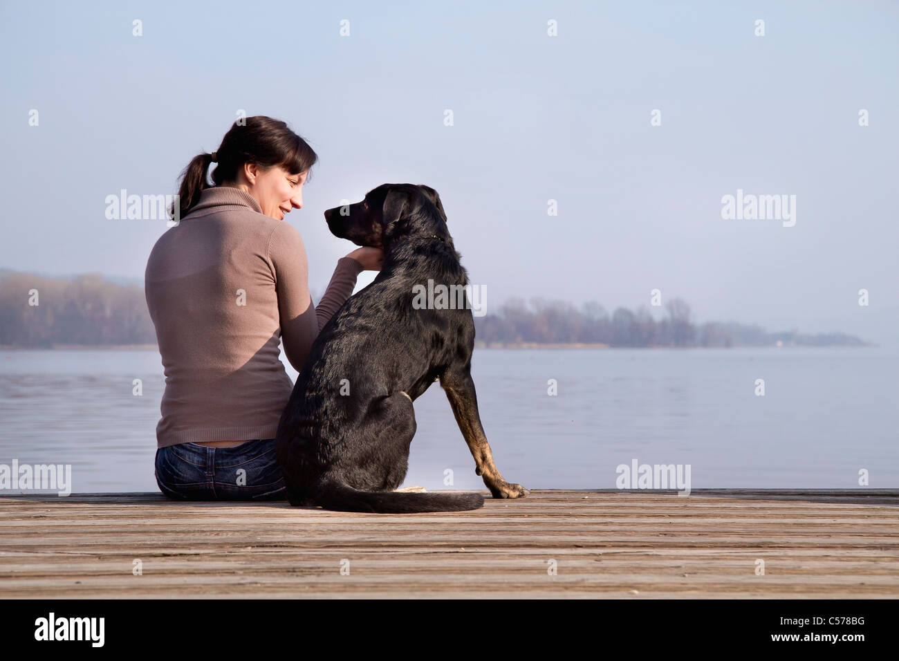 Donna seduta con il cane sul dock Foto Stock
