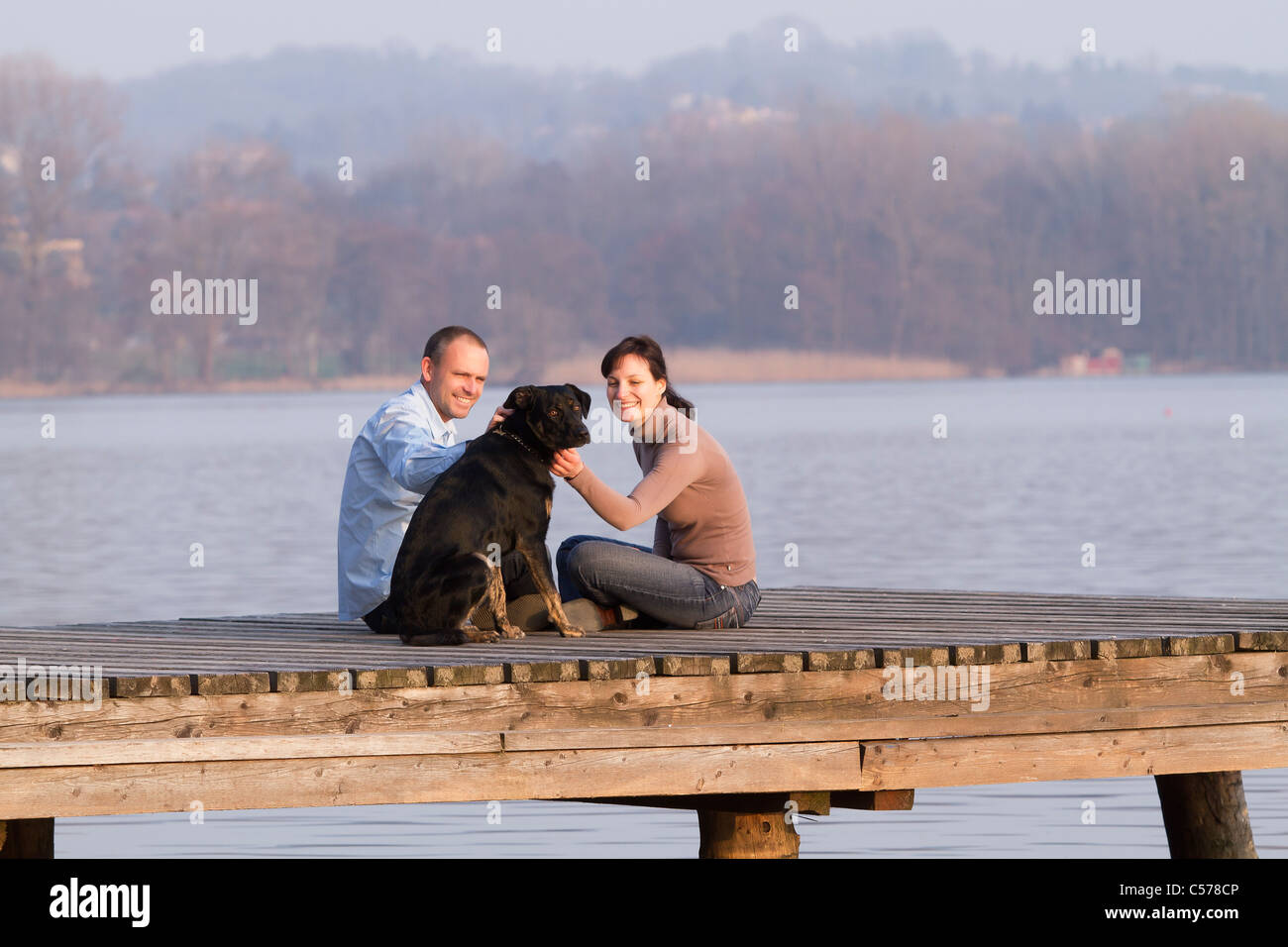 Giovane petting cane sul pontile sul lago Foto Stock