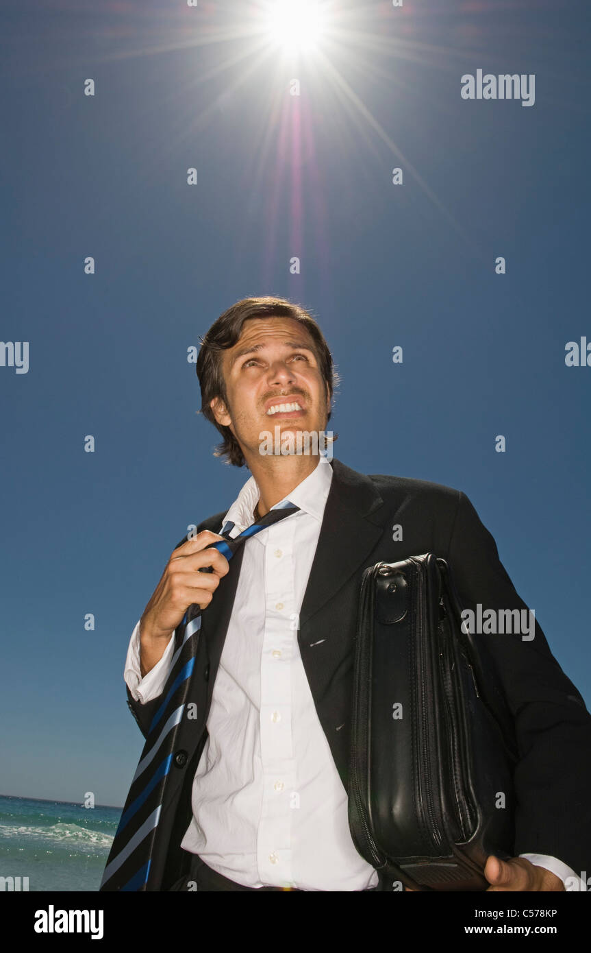 Imprenditore allentando la cravatta sulla spiaggia Foto Stock