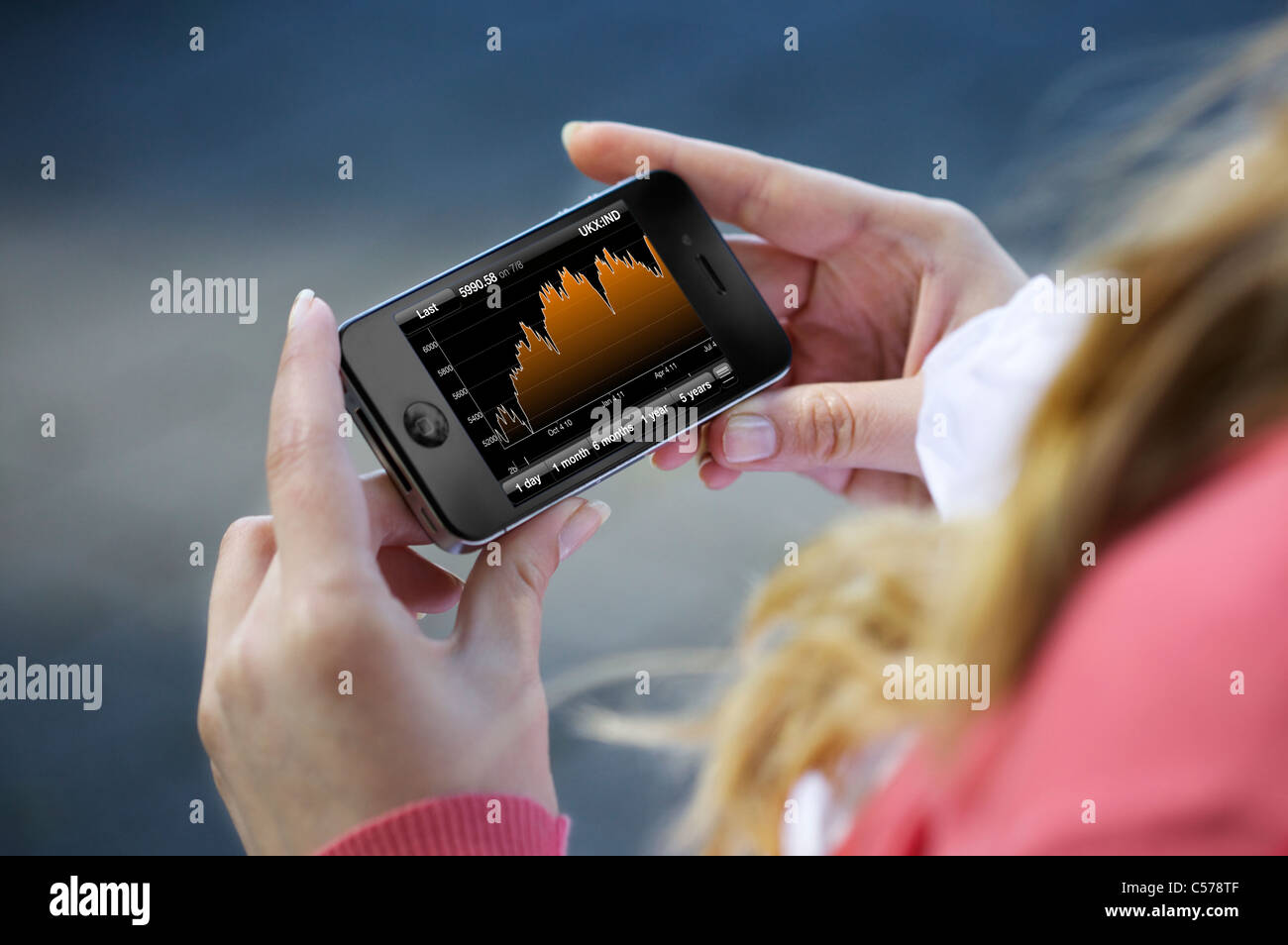 Vista ravvicinata di una donna controllo stock market con Bloomberg Finanza applicazione su un iphone 4 Foto Stock