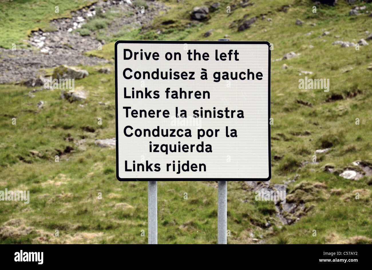Un cartello stradale multilingue che ricorda gli automobilisti a 'drive sulla sinistra " un uno svincolo della A82 in Glencoe, Scotland, Regno Unito. Foto Stock