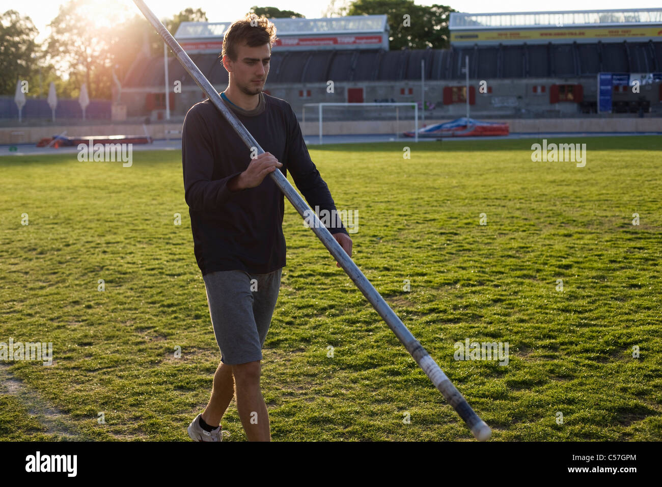 Uomo che cammina con la pole in erba dello stadio Foto Stock