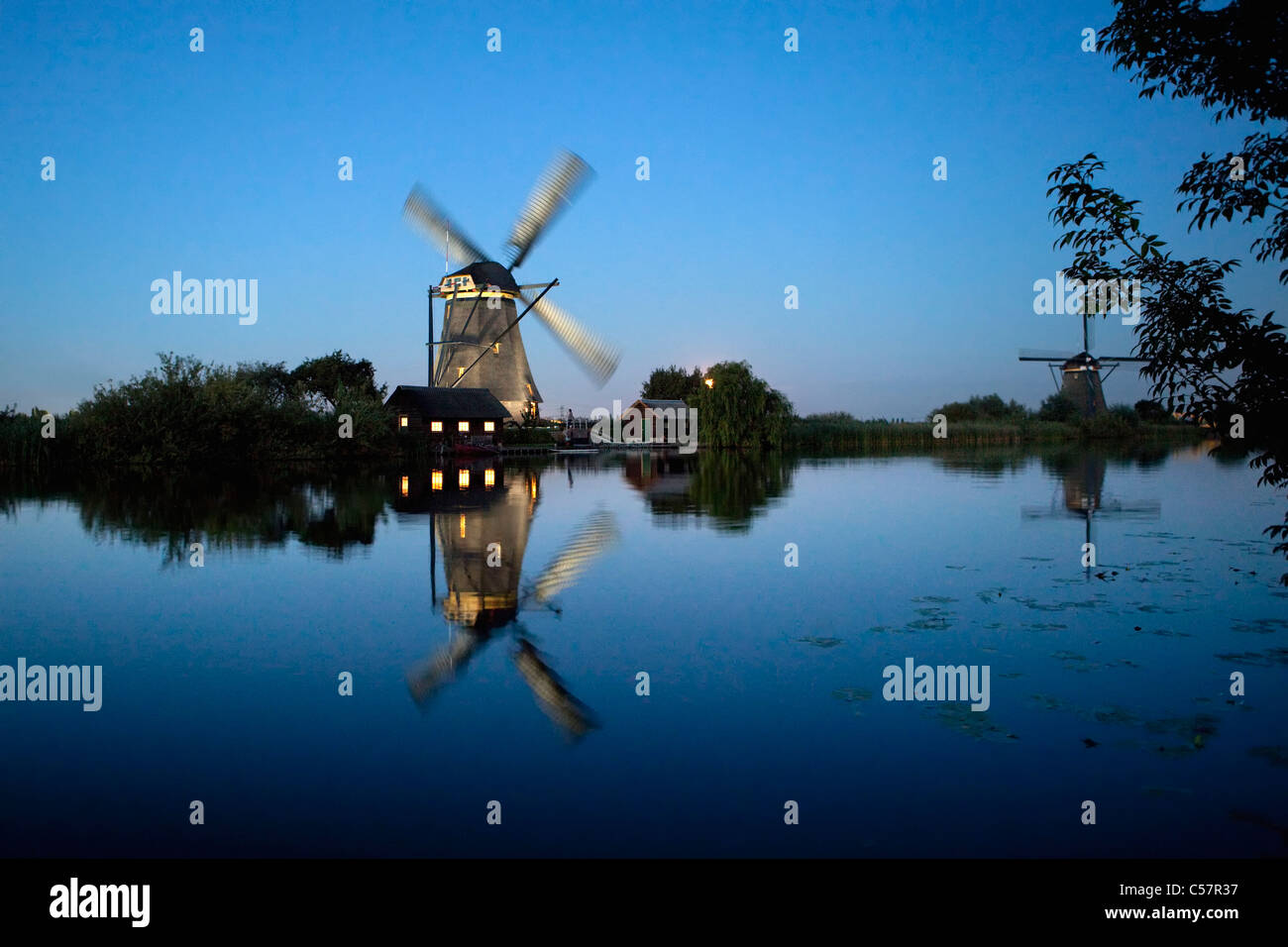 I Paesi Bassi, Kinderdijk, illuminato il mulino a vento, Sito Patrimonio Mondiale dell'Unesco. Foto Stock