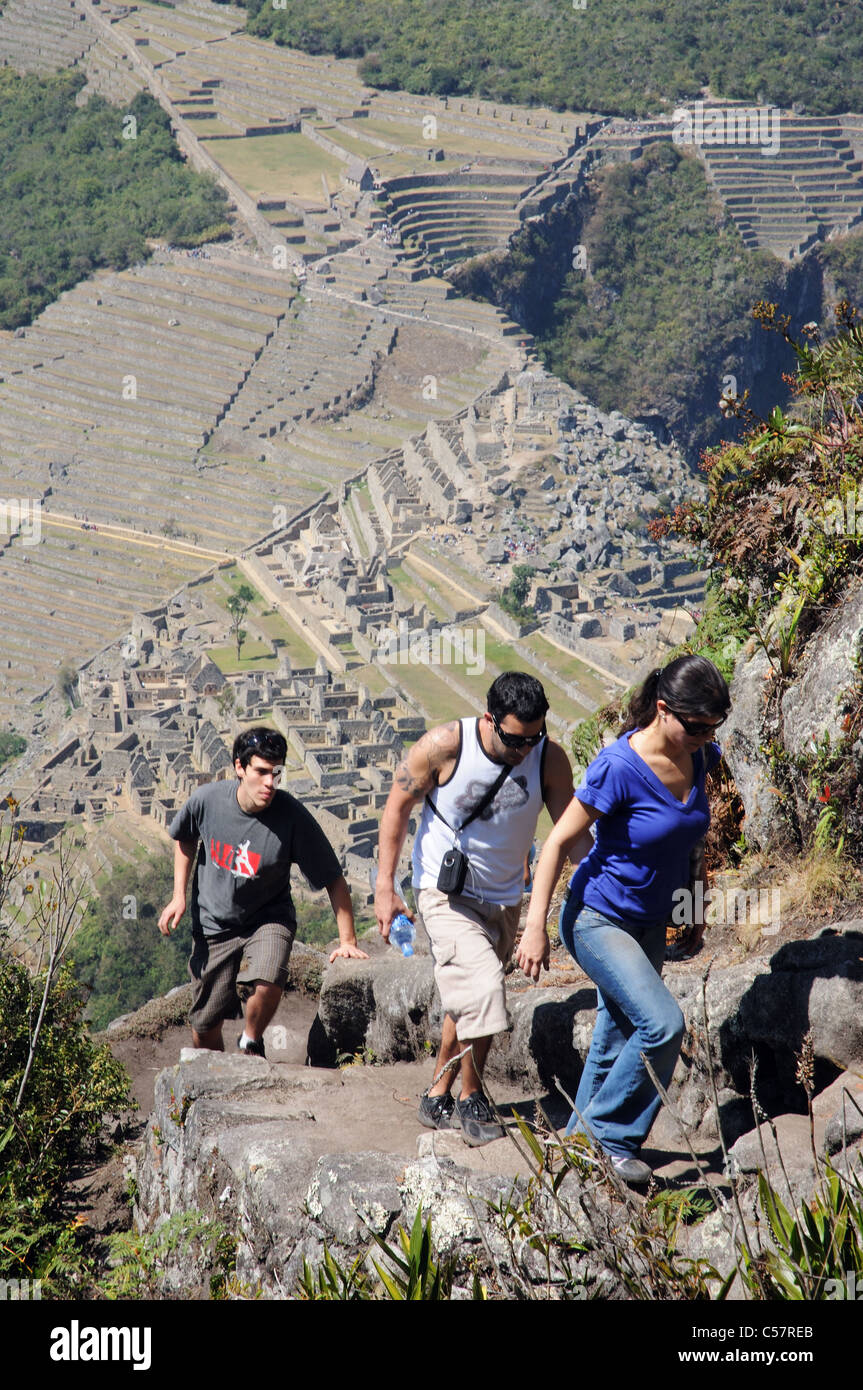 Tre persone sulla ripida salita Huayna Picchu con Macchu Picchu al di sotto di Foto Stock