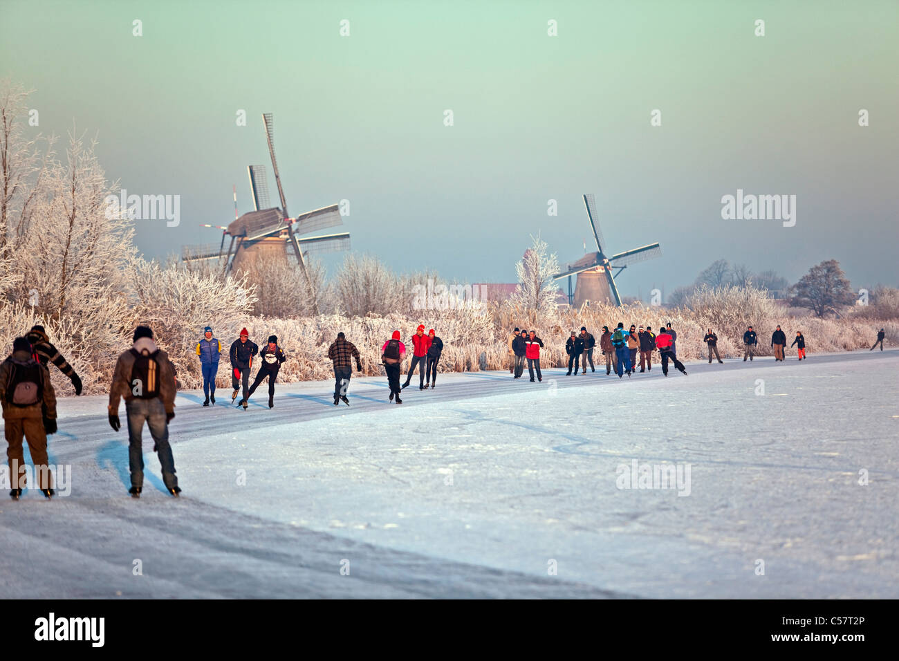 I Paesi Bassi, Kinderdijk, mulini a vento, Sito Patrimonio Mondiale dell'Unesco. Persone il pattinaggio su ghiaccio. Foto Stock
