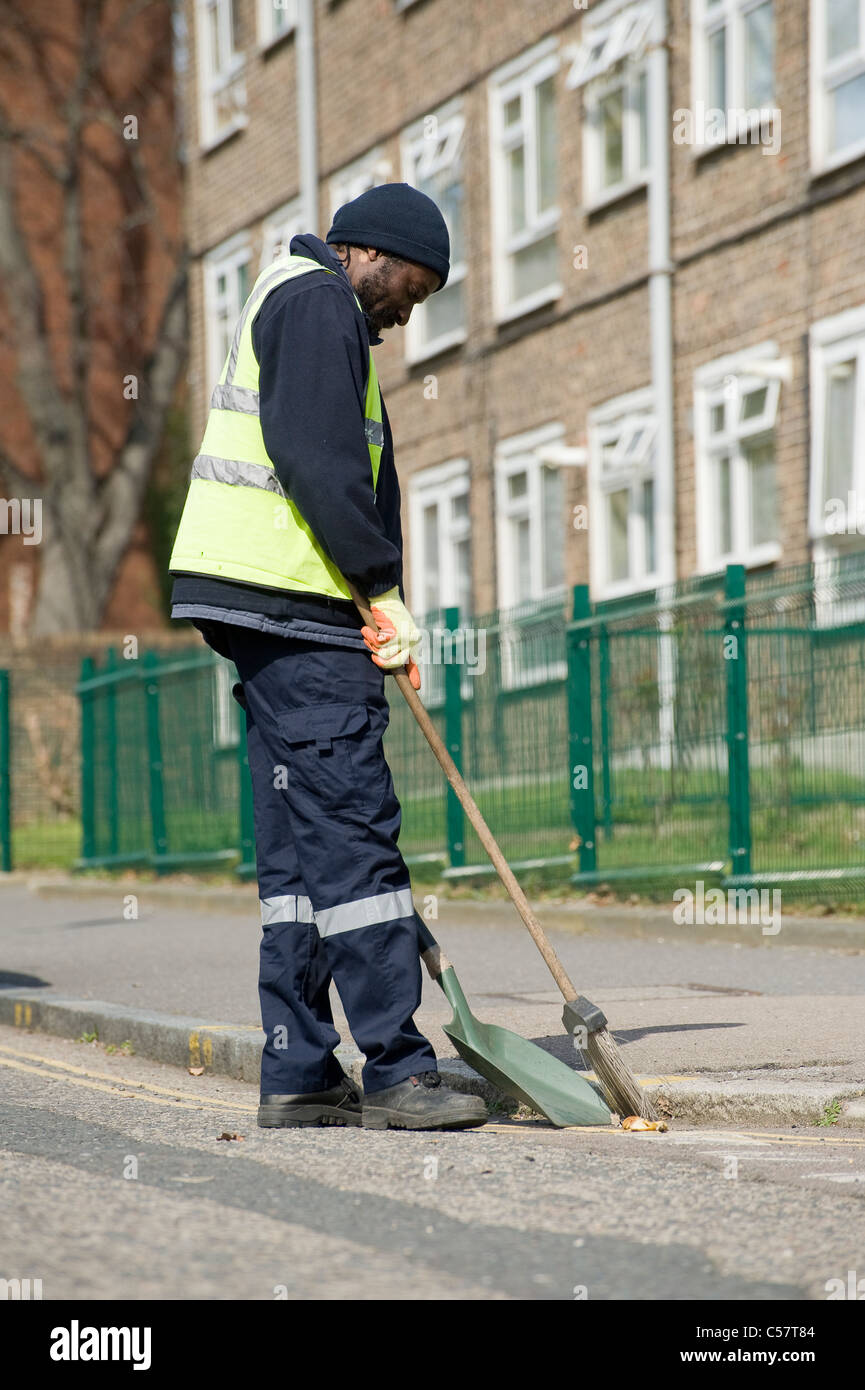 Consiglio di spazzamento lavoratore una strada in una zona suburbana di Inghilterra. Foto Stock