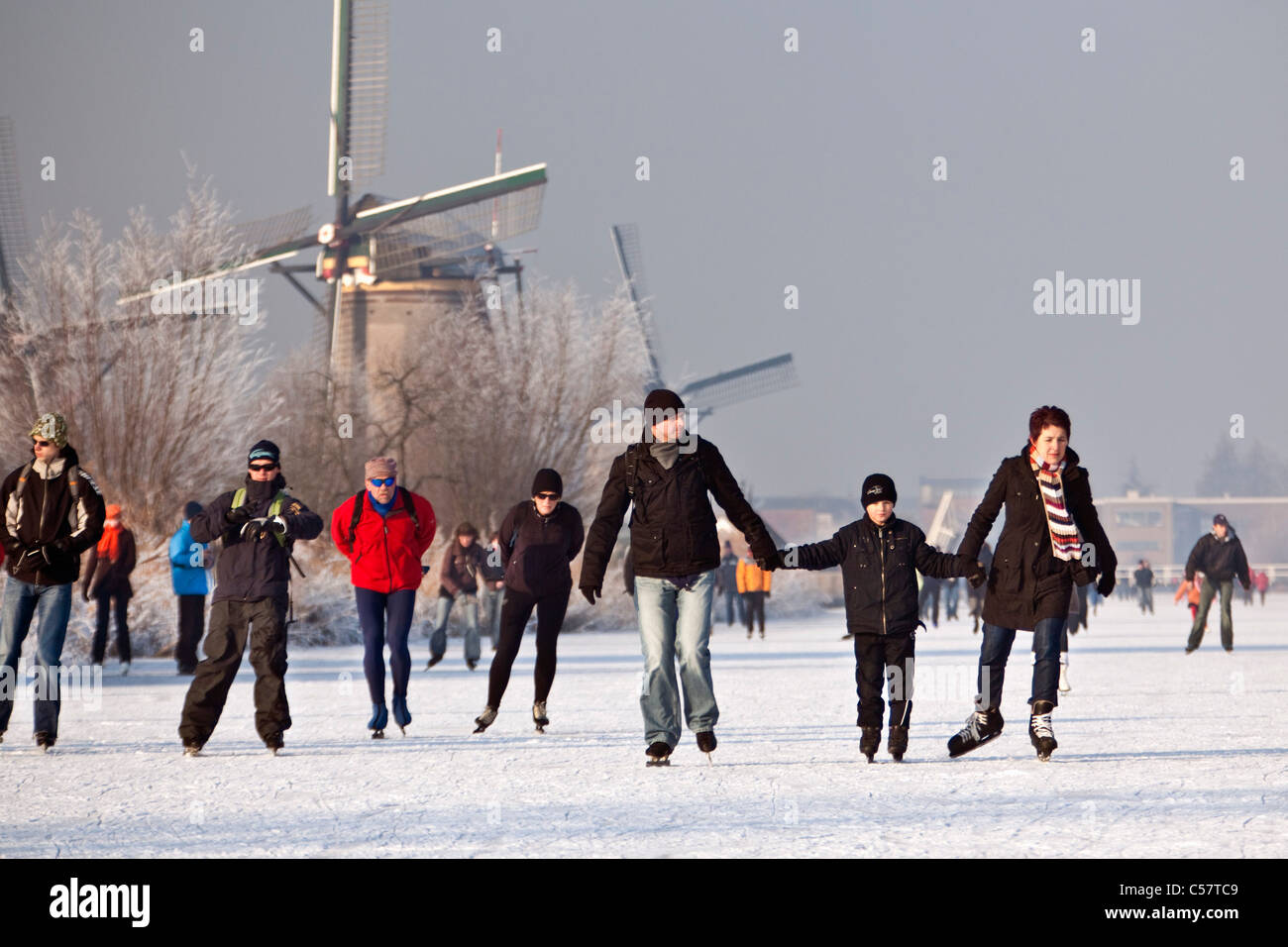 I Paesi Bassi, Kinderdijk, mulini a vento, Sito Patrimonio Mondiale dell'Unesco. Persone il pattinaggio su ghiaccio. Foto Stock
