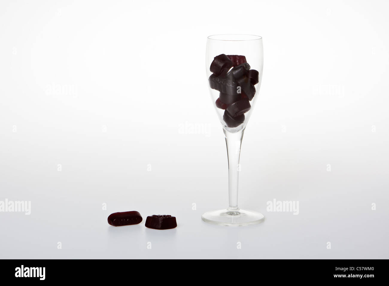 Il vino di vetro riempita con il vino nero gomme contro uno sfondo bianco. Foto Stock