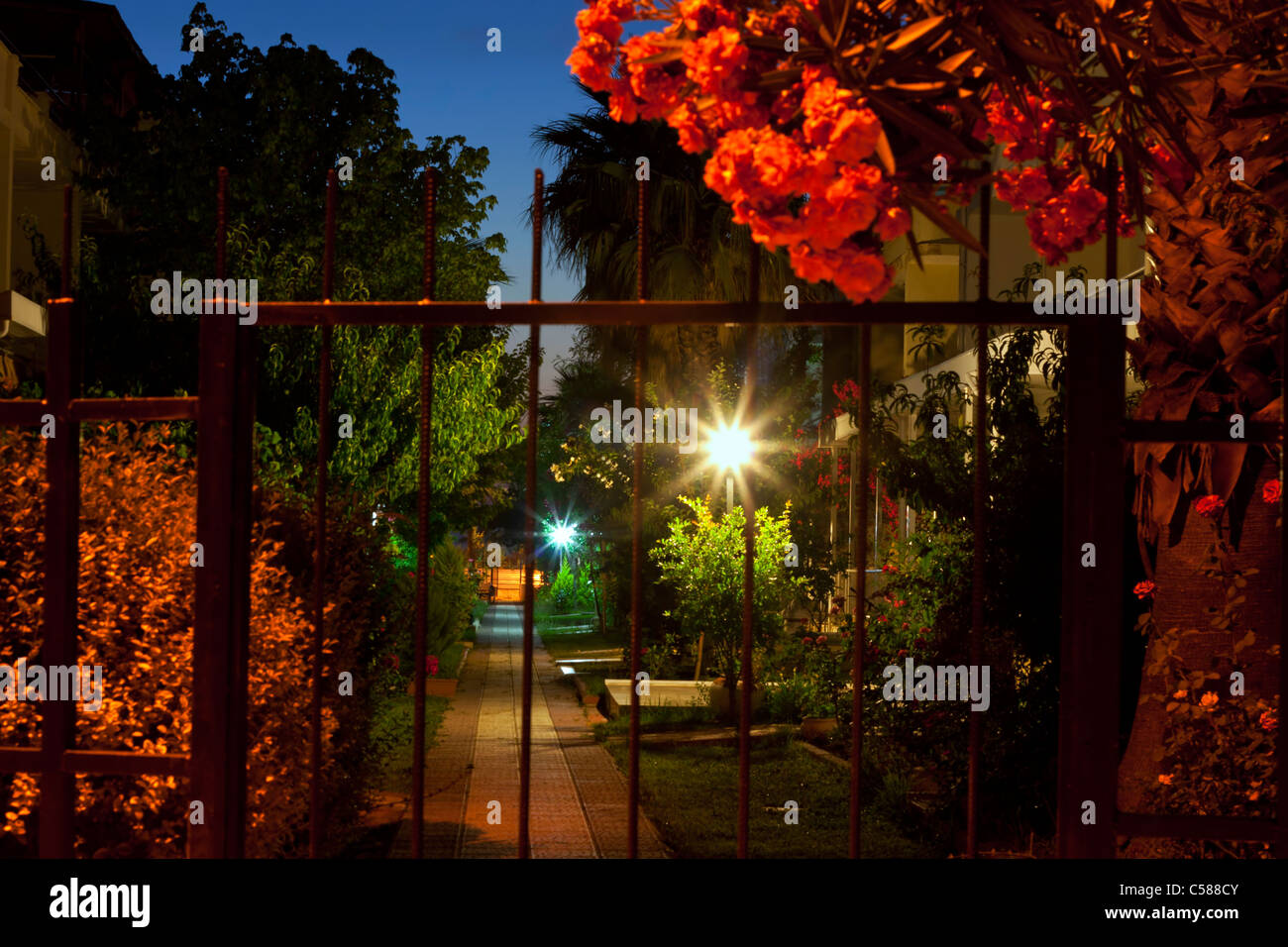 Guardando attraverso le porte a giardini colorati di notte Foto Stock